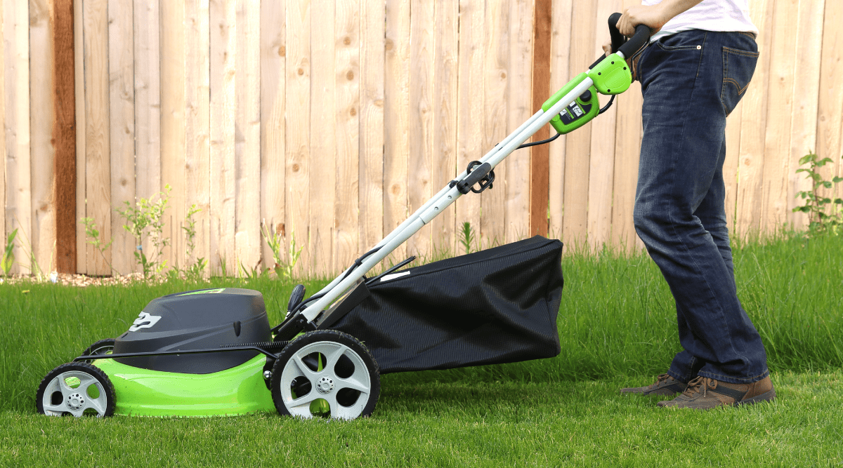 Man pushing lawnmower on grass