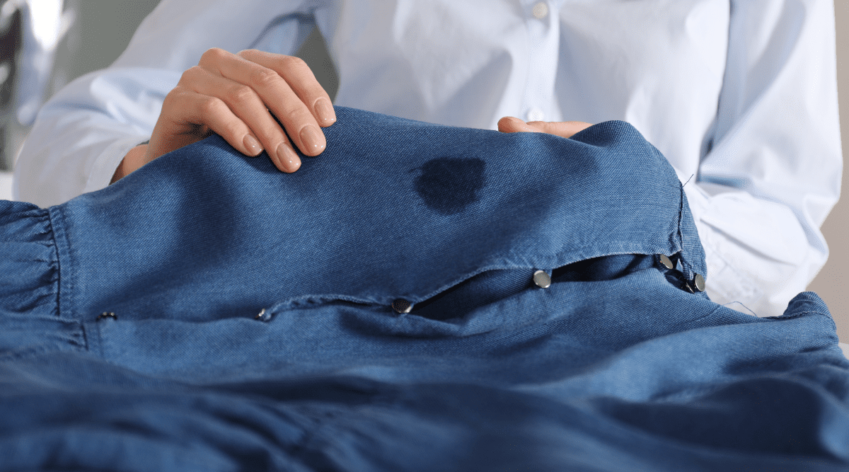 Person looking at grease stain on clothes