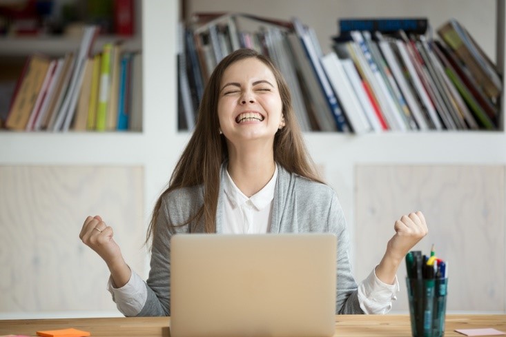 young woman happy in front of laptop