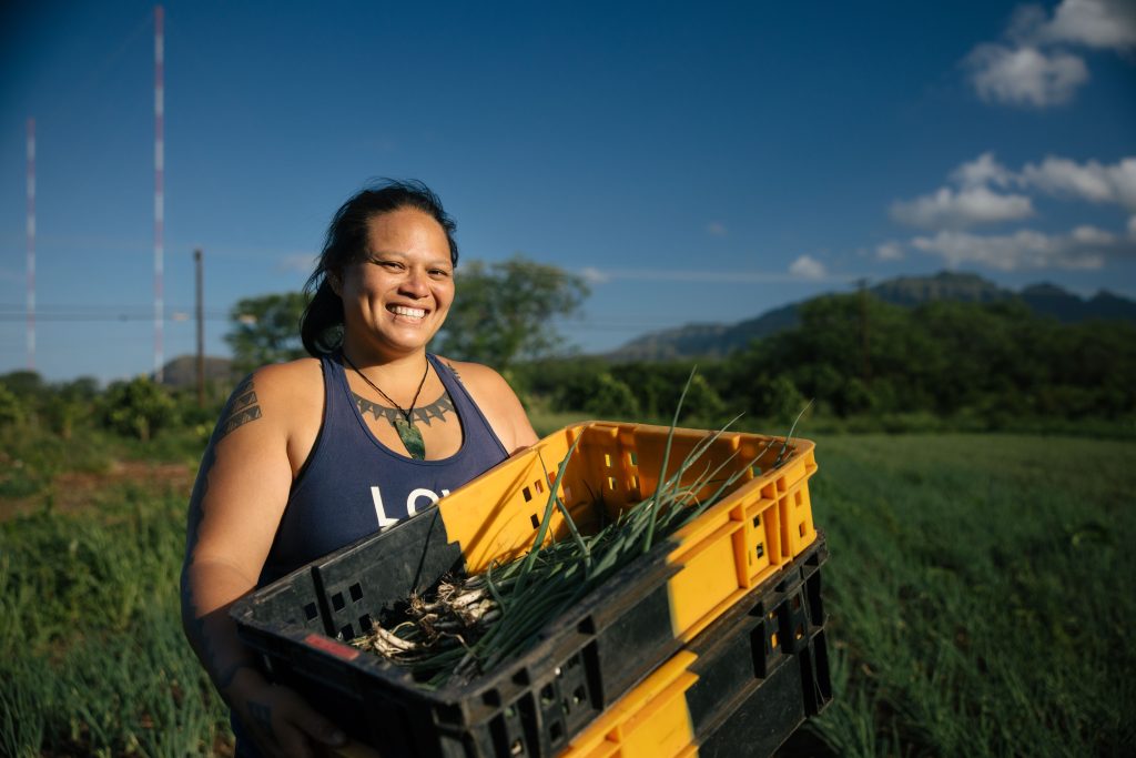 Hawaiian woman holding basket of produce and smiling