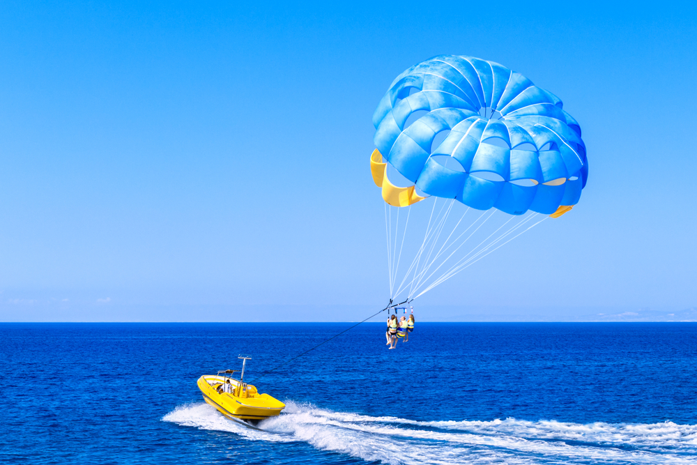 Person parasailing in the ocean with a yellow boat