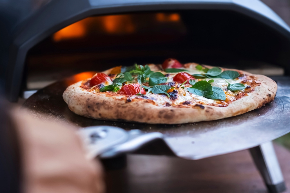 Fresh pizza being pull out of a wood fired oven
