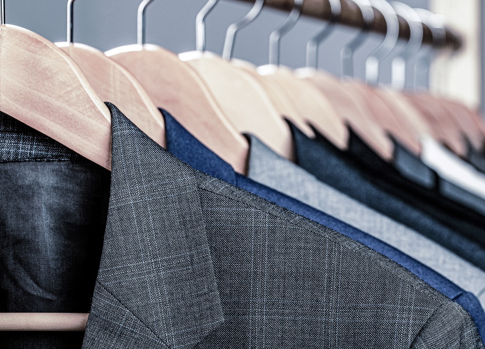 Different types of suits and tuxedos hung on a rack