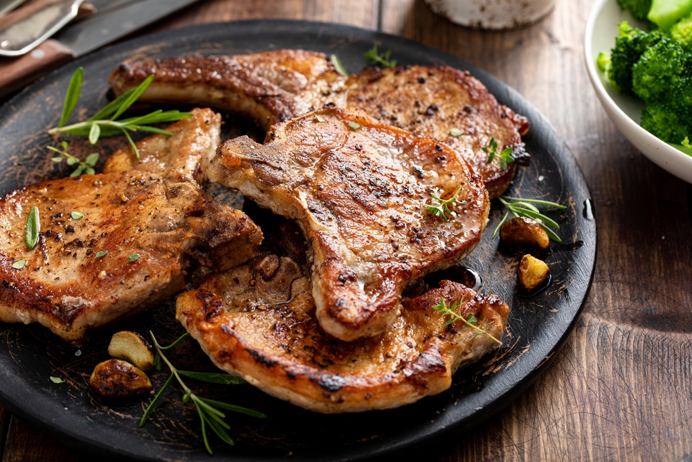 Pork chops on a black plate on a wooden table